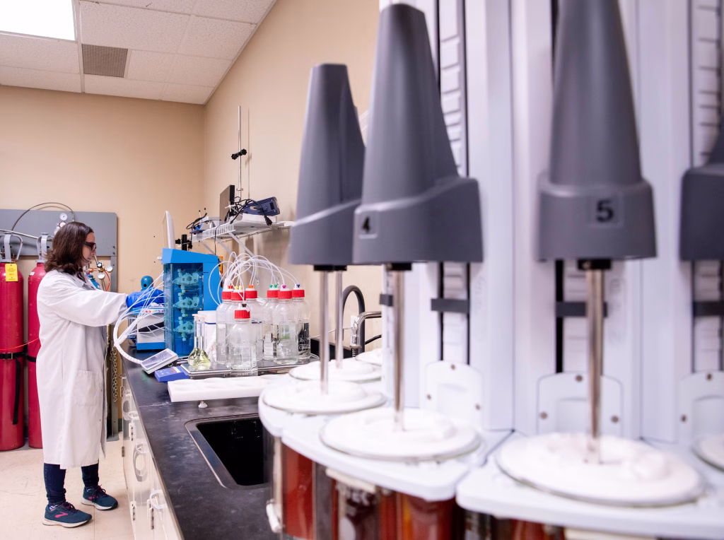 CMC scientist executing drug development studies in lab with dissolution apparatus in the foreground