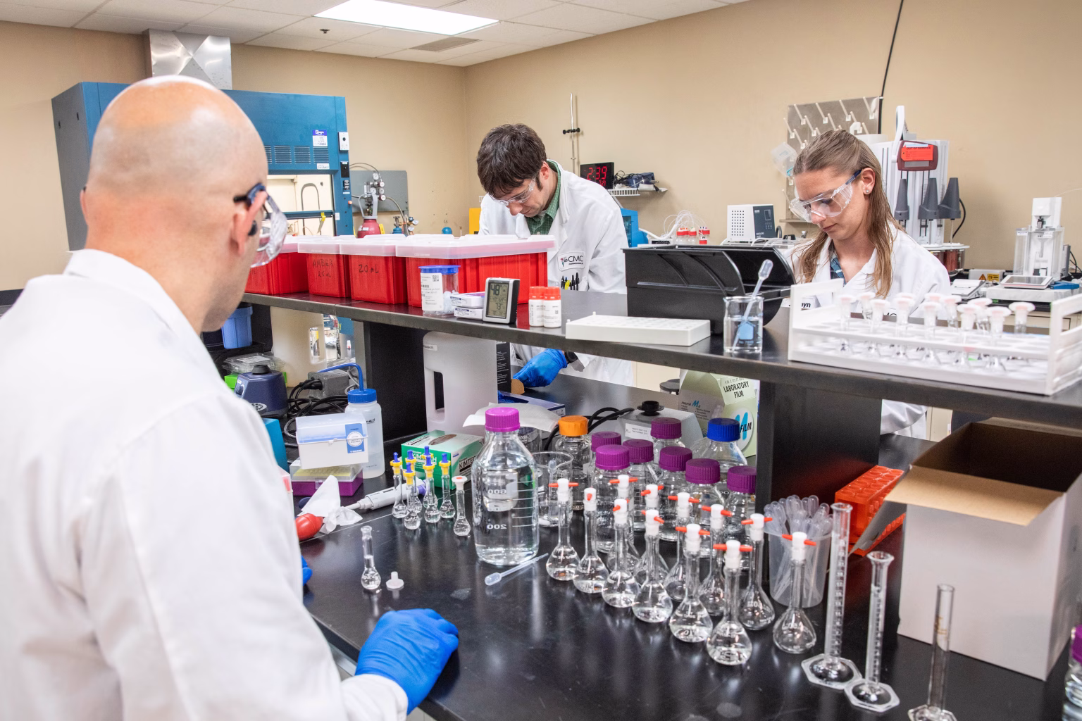 Three drug development chemists in laboratory