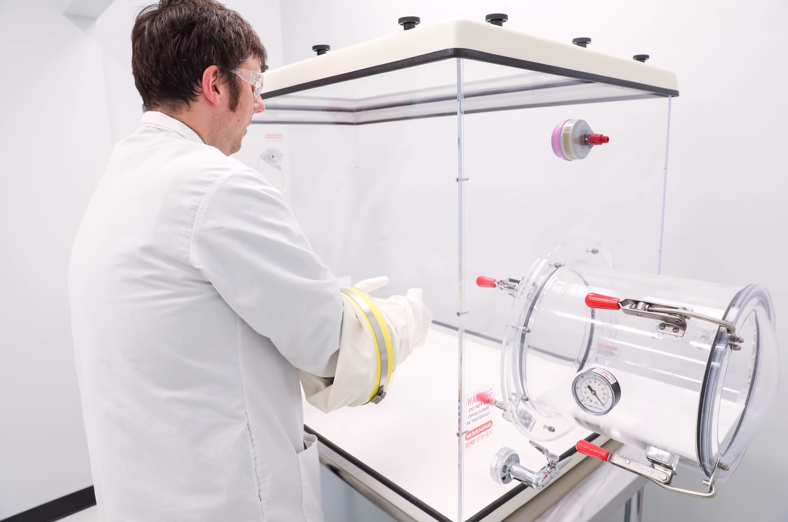 scientist in laboratory using glove box to handle highly potent compounds